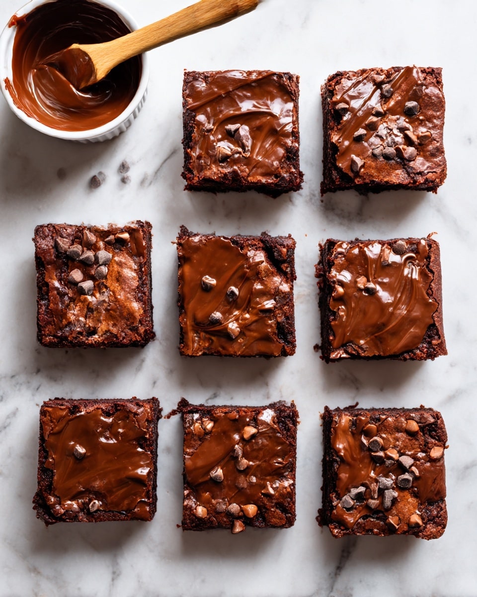 Eight thick, square brownie pieces are placed closely together on a white marbled surface, arranged in two neat columns and four rows. Each brownie has a rich, dark brown, dense base with a shiny, glossy layer of melted chocolate on top, decorated with small chocolate chips and bits scattered over the surface. To the top left of the brownies, there is a small white ramekin filled with smooth melted chocolate and a wooden spatula resting inside. The background and surface around the brownies are clean with a white marbled texture. Photo taken with an iphone --ar 4:5 --v 7