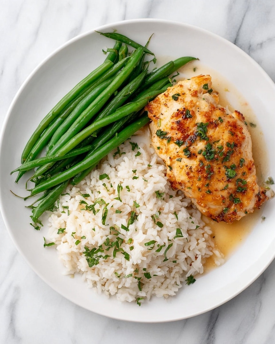 A white plate sits on a white marbled surface, holding three main parts: a portion of long green beans arranged in a neat bundle on the left; a heap of fluffy white rice speckled with finely chopped green herbs positioned below the green beans and slightly overlapping them; and a golden-brown cooked chicken piece on the right, with a crispy textured surface dotted with green herb bits and a light drizzle of sauce around it. The colors contrast nicely with the clean white plate and marble background, creating a fresh and appetizing look. Photo taken with an iphone --ar 4:5 --v 7