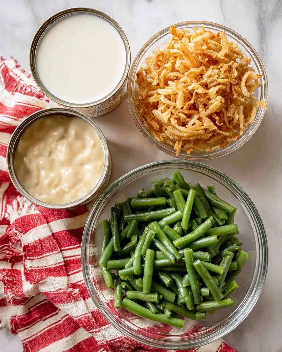 A clear glass bowl sits at the bottom filled with canned green beans, cut into short green pieces that show a smooth texture. Above, to the right, there is a clear glass measuring cup filled with crispy fried onions in light golden brown colors, with a crunchy look. On the left in the upper part, two opened cans show thick cream of mushroom soup with a creamy, pale beige texture inside. Next to the cans, there is an open can filled with smooth white evaporated milk. All these items are placed on a white marbled texture surface with a red and white striped cloth partially underneath the cans and cup. photo taken with an iphone --ar 4:5 --v 7