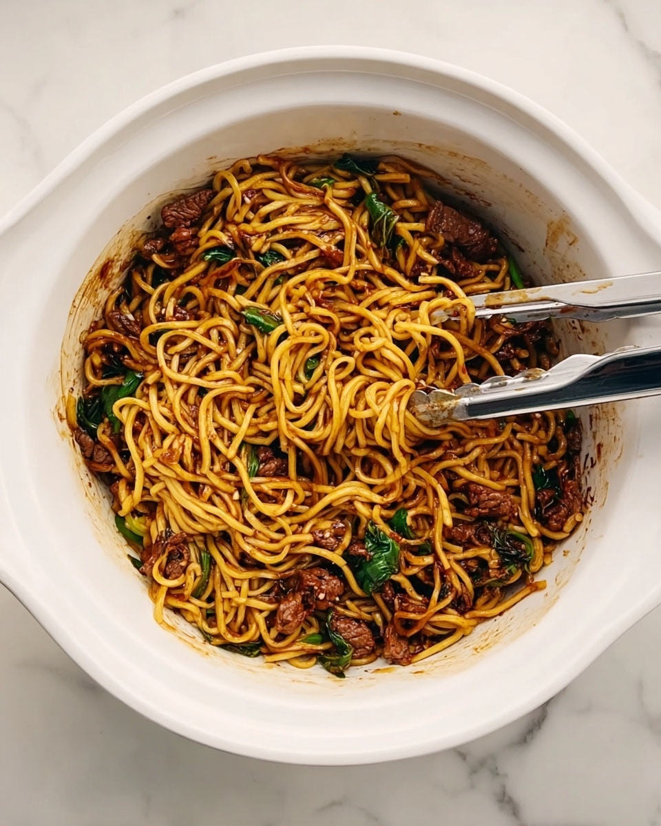 A white round bowl filled with long, yellowish noodles mixed with pieces of dark brown meat and green leafy vegetables. The noodles look soft and slightly shiny, coated evenly with a dark sauce that clings to them. Two metal tongs rest inside the bowl, partially submerged in the noodles. The bowl sits on a white marbled surface. Photo taken with an iphone --ar 4:5 --v 7