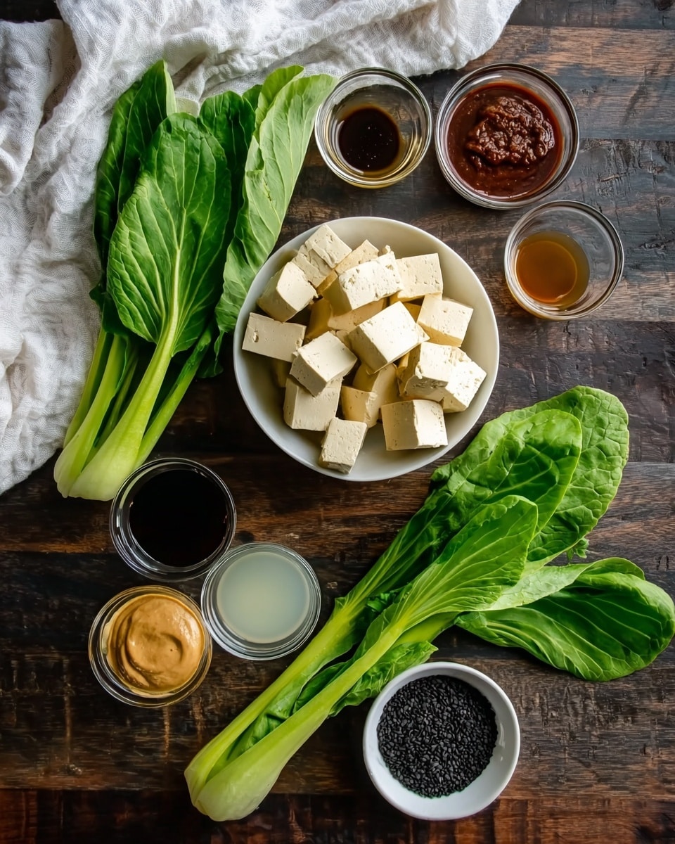The image shows several ingredients neatly placed on a dark wooden surface with a white marbled texture blanket on the left side. At the center, there is a white bowl filled with pale yellow tofu cubes. To its left, there are two fresh green leafy vegetables, with long stalks and broad green leaves. Surrounding the bowl and vegetables are small glass bowls holding different sauces and liquids: at the top, a dark soy sauce, on the top right a reddish-brown paste, below it a creamy light brown sauce, a dark liquid beside it, a very small bowl with a darker liquid close to the center, and at the bottom left a bowl with a translucent white liquid. At the bottom right is a white bowl filled with black seeds. The mix of colors is green, yellow, brown, black, and white, arranged carefully to show each element clearly. Photo taken with an iphone --ar 4:5 --v 7