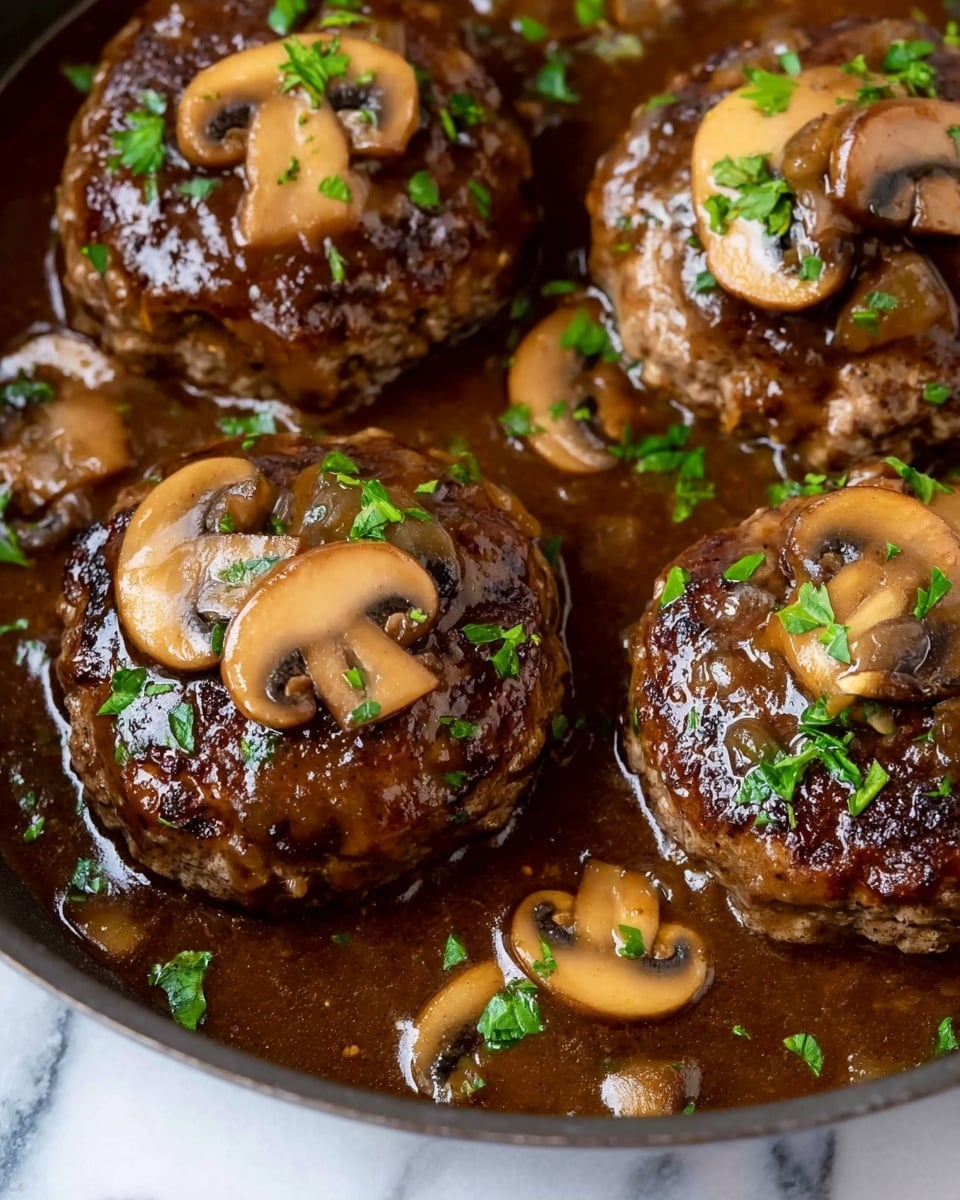 This image shows a close-up of four round meat patties cooked in a dark brown mushroom sauce inside a pan. Each patty is topped with slices of cooked light tan mushrooms and small green parsley leaves, offering a mix of soft and fresh textures and tones. The sauce is thick and glossy, covering parts of the patties and pooling around them. The pan's edge is visible with a smooth, dark surface. The background is a white marbled texture. photo taken with an iphone --ar 4:5 --v 7