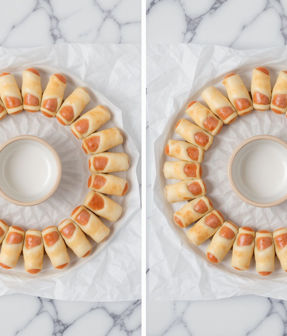 Mini sausages wrapped with dough are arranged in a circular pattern on crinkled white baking paper on a white marbled surface. Each piece shows light brown sausages partially covered by pale golden dough, wrapped tightly around the sausages in small spiral layers. The left image shows the circle with a small empty white wooden bowl in the center, while the right image shows the same circle without the bowl, highlighting the even spacing of the mini wrapped sausages. photo taken with an iphone --ar 4:5 --v 7