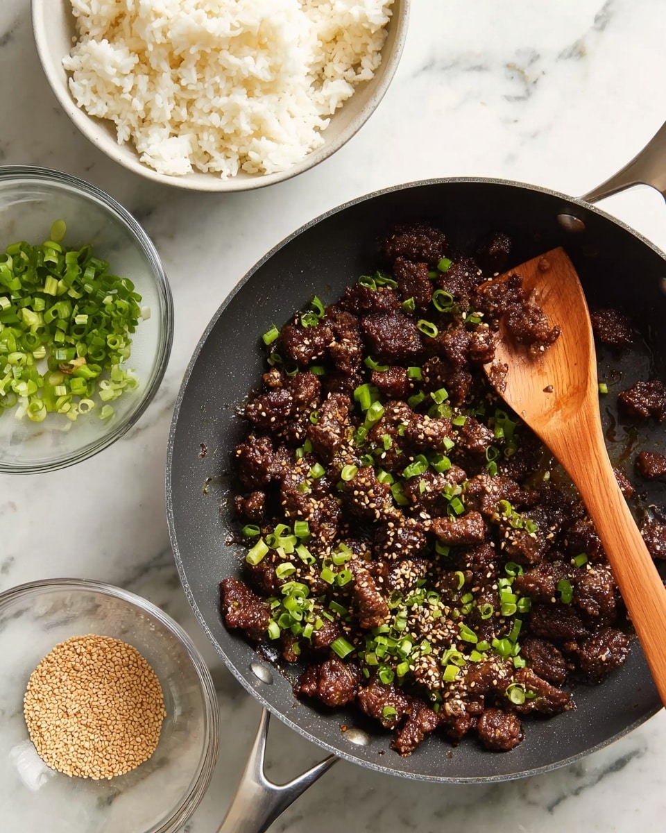 A black pan filled with cooked small dark brown meat pieces sprinkled with bright green chopped scallions and some sesame seeds. A wooden spoon rests in the pan, partially stirring the meat. Nearby, a small clear bowl holds light brown sesame seeds scattered a bit around it, and another clear bowl contains more chopped green scallions. Above the pan, a round white bowl is filled with plain white rice. All items are placed on a white marbled surface. photo taken with an iphone --ar 4:5 --v 7