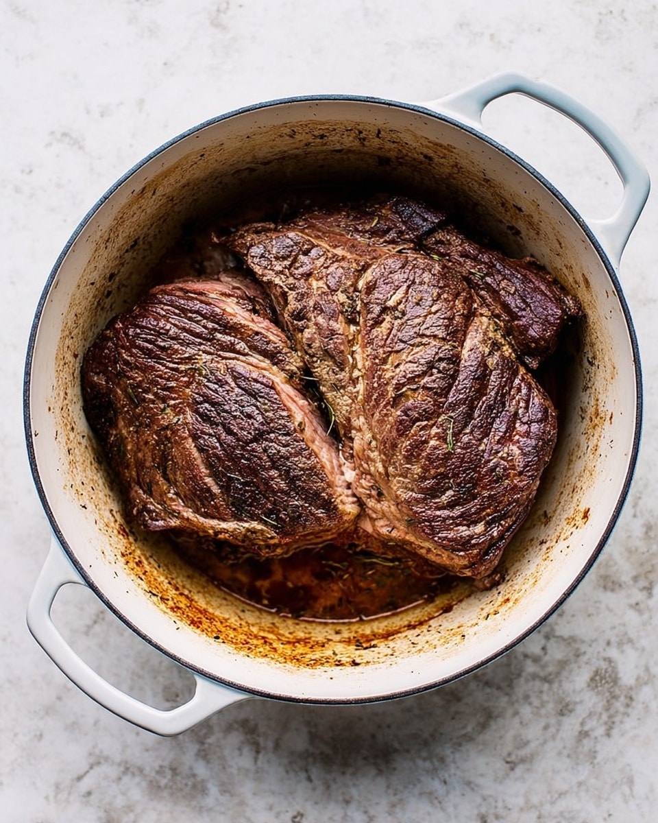 A large piece of cooked beef lies inside a white oval pot with two handles. The beef has dark brown, seared areas with a textured surface showing grill marks and cooked lines. The inner part of the meat is lighter brown with some pinkish spots. The white pot has some browned spots on the inside edges from cooking. The pot sits on a white marbled surface. photo taken with an iphone --ar 4:5 --v 7
