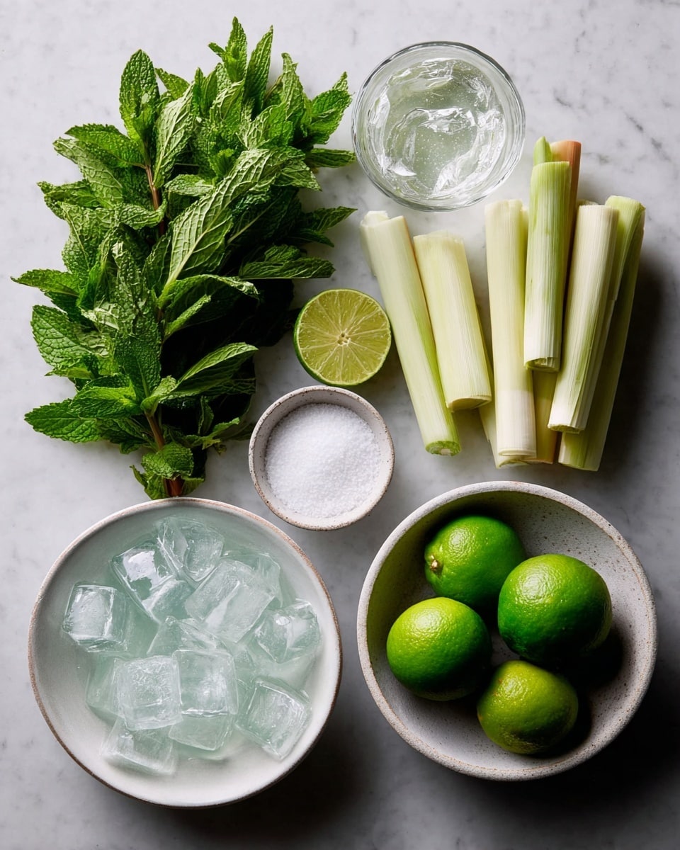 A white marbled surface holds a collection of ingredients: a bunch of fresh green mint leaves with detailed texture on the leaves, a white bowl filled with many pale green cut lemongrass stalks standing upright, a clear glass filled with ice cubes that are shiny and translucent, a small white bowl with coarse white salt, a white bowl containing four whole bright green limes, and a lime half with a juicy, pale green interior placed between the bowls. photo taken with an iphone --ar 4:5 --v 7