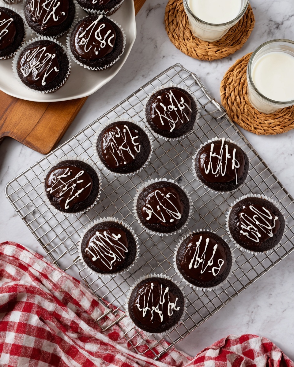 A metal cooling rack holds ten chocolate cupcakes with dark, shiny chocolate frosting, each topped with a white icing squiggly line across the top. The frosting has a smooth, glossy texture. The cupcakes sit in white paper liners and are arranged in a 4 by 3 grid with two cups missing at the bottom right and upper left corners. To the left, a white plate sits on a wooden board holding additional cupcakes with the same design. Nearby, two glasses of milk rest on round wooden coasters with woven centers, placed on a white marbled surface. A red and white checkered cloth is partially visible at the bottom right corner of the image. photo taken with an iphone --ar 4:5 --v 7