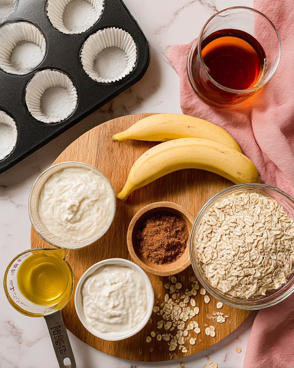 The image shows a wooden board on a white marbled surface with two peeled bananas placed side by side near the center. Below them is a small white bowl filled with a brown powder, likely cinnamon mixed with other spices, and to the left is a glass bowl with white creamy yogurt. Next to the yogurt is a metal measuring cup holding a yellow liquid, probably oil or honey. A large glass bowl filled with rolled oats is positioned on the right side of the board, with some oats scattered around it. Above the bananas, there's a clear glass container filled with a dark amber liquid and a wooden bowl with a smaller amount of the same liquid. To the upper left, a black muffin tray holds white paper liners. A pink cloth is spread under part of the tray. The setup is neatly arranged and ready for baking. Photo taken with an iphone --ar 4:5 --v 7