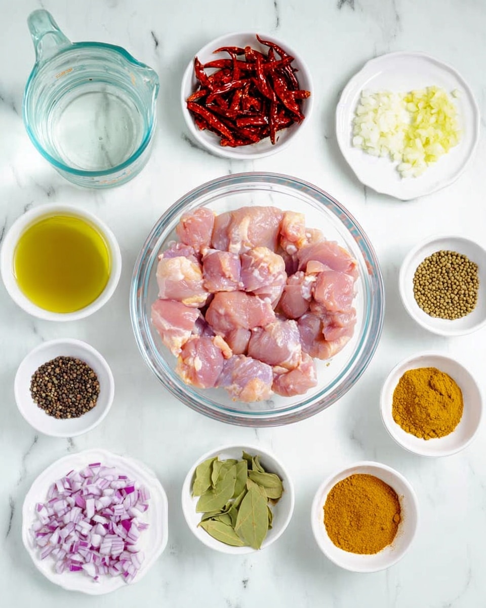 The image shows a clear glass bowl in the center with raw pink chicken pieces arranged inside. Surrounding the bowl are small white bowls and plates containing various ingredients: to the top left, a clear measuring jug with water; to the middle left, a white bowl with dried red chilies; below it, a white plate with piles of black peppercorns, coriander seeds, cumin seeds, and fennel seeds. On the top center, there is a small white bowl of minced garlic, next to a small glass bowl of golden oil. To the right, there are three more small white bowls holding chopped red onions, yellow curry powder, salt, and bright green curry leaves. The surface is a white marbled texture. photo taken with an iphone --ar 4:5 --v 7