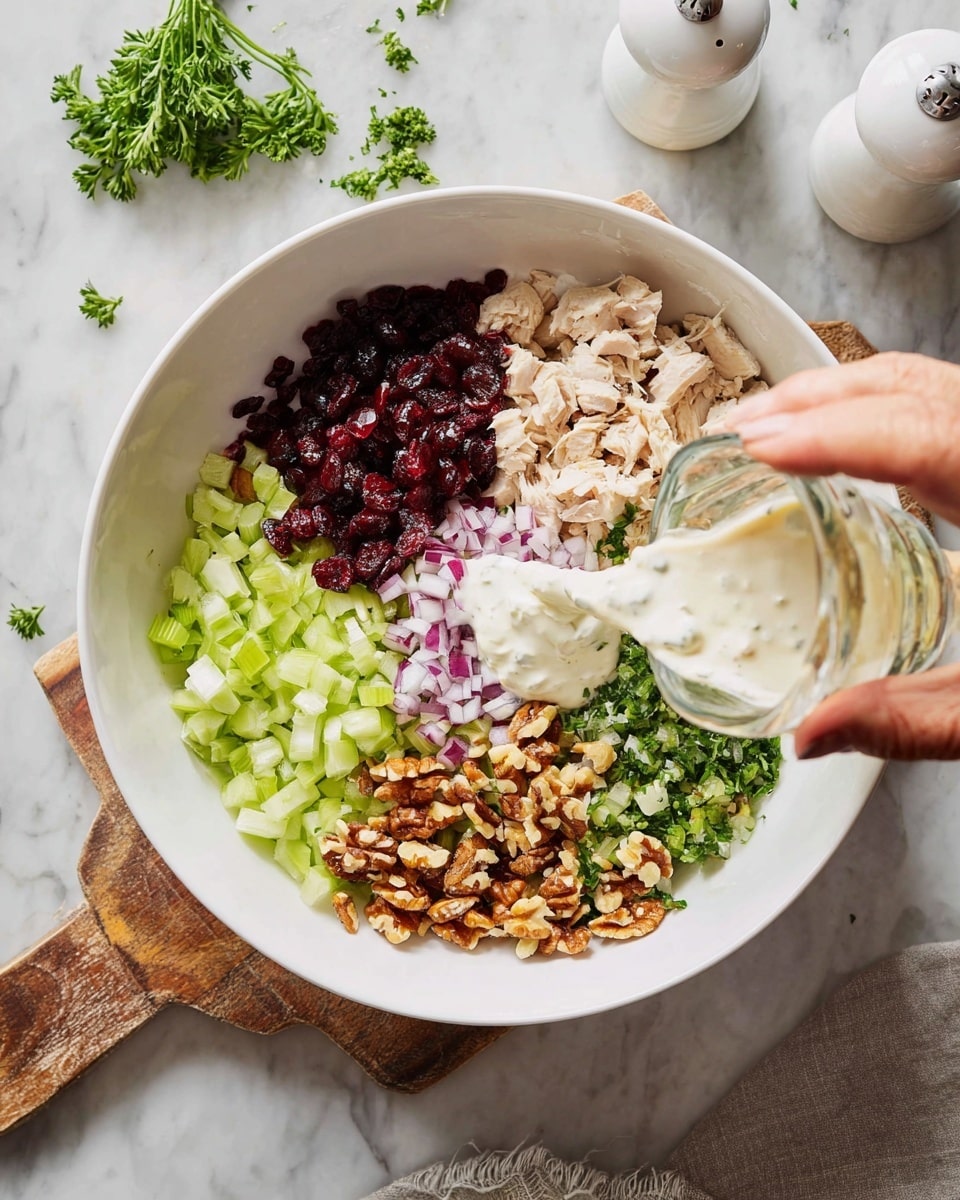 In a white bowl placed on a wooden board over a white marbled surface, there are seven colorful layers of ingredients separated neatly: finely chopped light green celery, dark red dried cranberries, chopped brown nuts, chopped green parsley, chopped light purple onion, creamy white yogurt, and small pieces of light beige cooked chicken. A woman’s hand is pouring a clear liquid from a small glass container into the bowl. In the background, there is a white salt shaker and some parsley scattered around. photo taken with an iphone --ar 4:5 --v 7