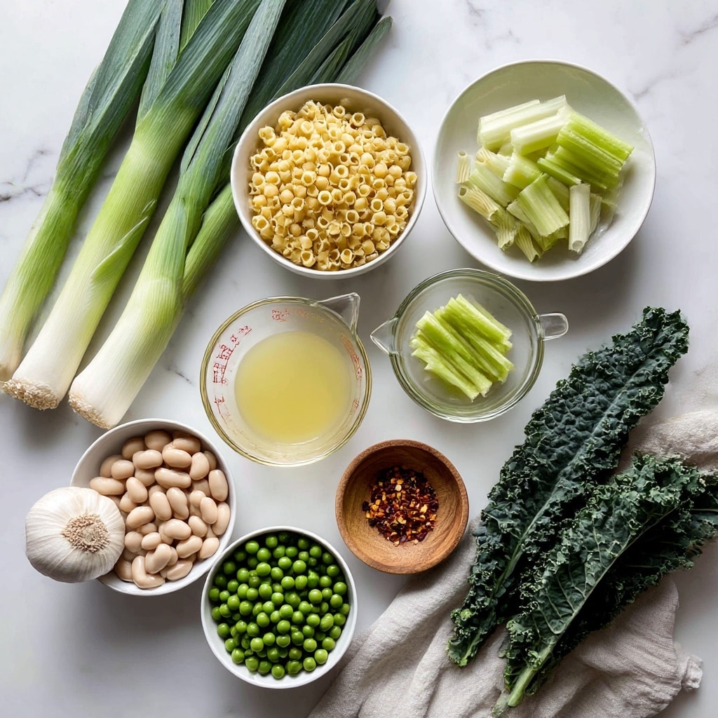The image shows many cooking ingredients on a white marbled surface. At the top left, there are three long green leeks with white bottoms. Below them is a white bowl filled with small uncooked pasta pieces that are yellow. To the right, a small glass bowl holds pale green sliced celery. Below it is a glass measuring cup with light yellow broth. Near the center, there is a small wooden bowl with red chili flakes. Below and slightly to the left is a white bowl full of bright green peas. At the bottom left, a white bowl holds beige large beans. To the left of the peas and beans, a whole garlic bulb rests on the surface. On the bottom right, fresh dark green kale leaves are placed, with a beige cloth partially covering the bottom part. photo taken with an iphone --ar 4:5 --v 7