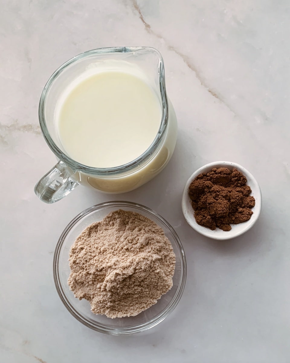 A clear glass pitcher filled with white milk sits on the left side of a white marbled surface. To the right and slightly below it, a small white bowl contains a fine dark brown powder. Below both items, a clear glass bowl holds a larger amount of light brown powder with a crumbly texture. The arrangement forms a loose triangle on the white marbled background photo taken with an iphone --ar 4:5 --v 7